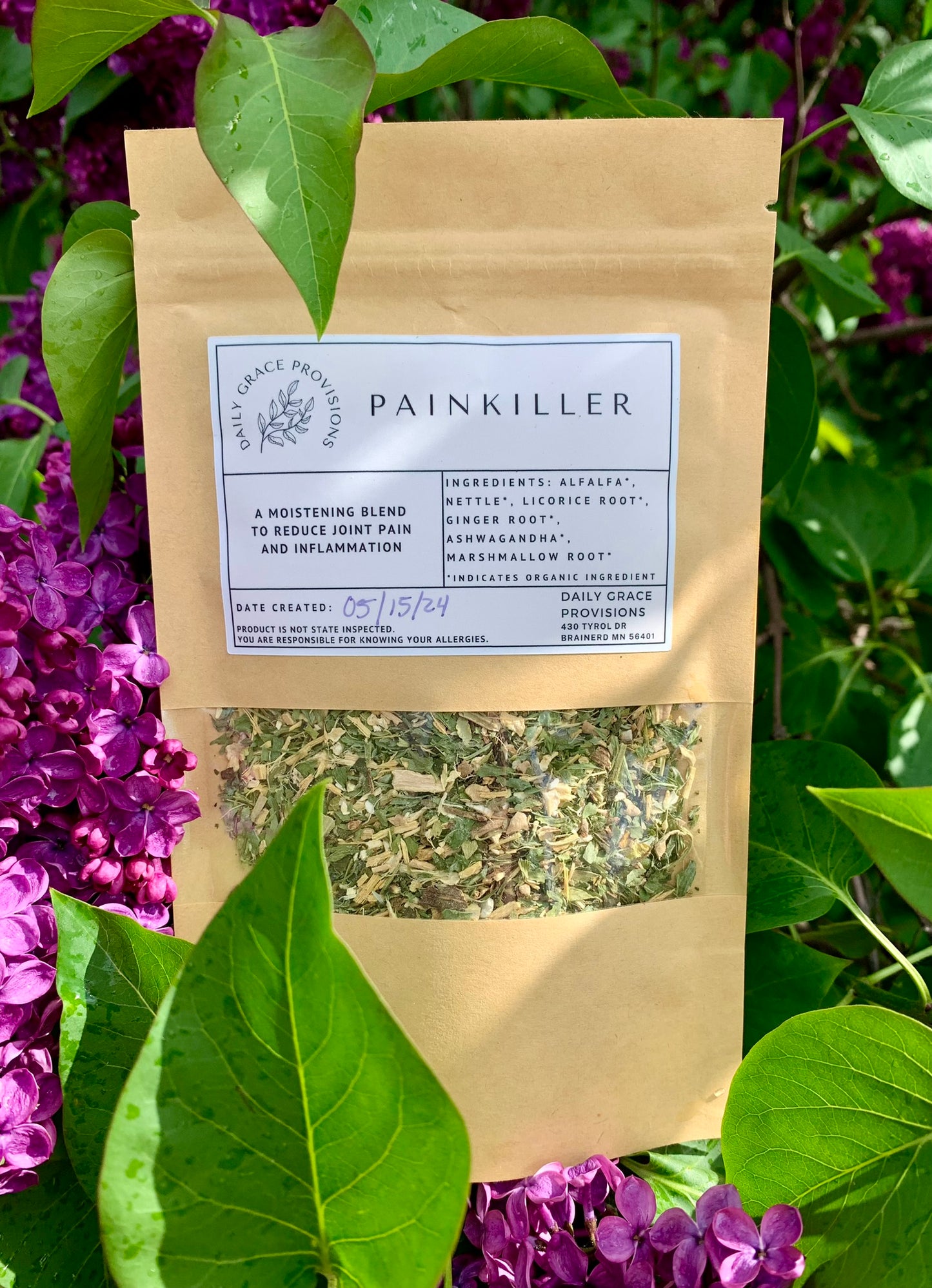 Painkiller Tea packaging amongst lilacs